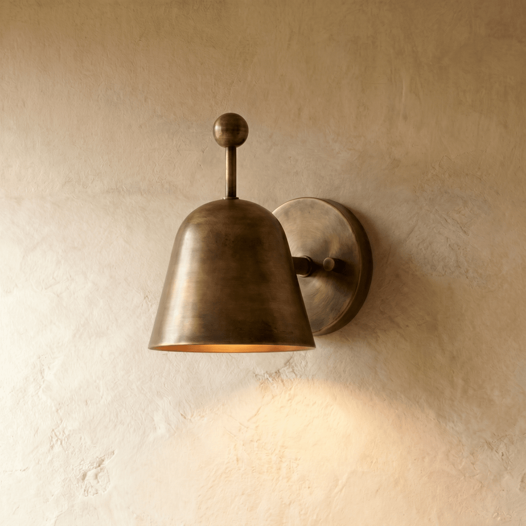 Clérachic wall lamp in vintage brass with a bell-shaped shade tilted forward on a round wall plate.