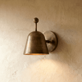 Clérachic wall lamp in vintage brass with a bell-shaped shade tilted forward on a round wall plate.