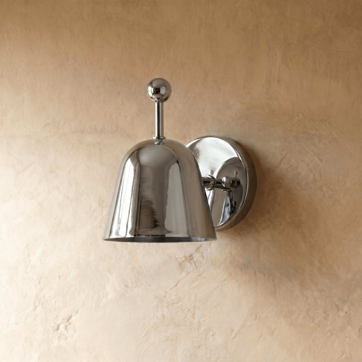 A chrome Clérachic wall lamp viewed from a different angle, its glossy bell shade tilted forward.