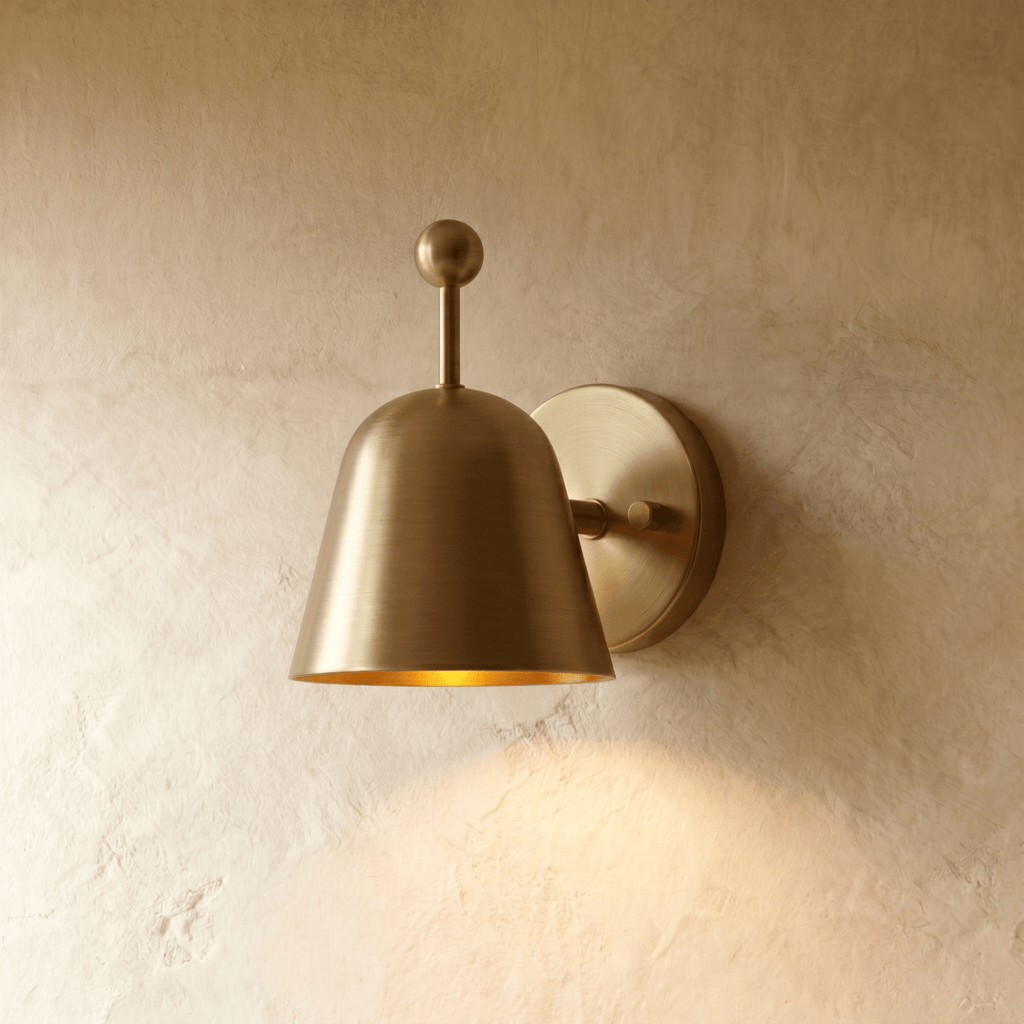 Clérachic wall lamp in polished brass, its bell shade angled down from a slim ball-topped arm.