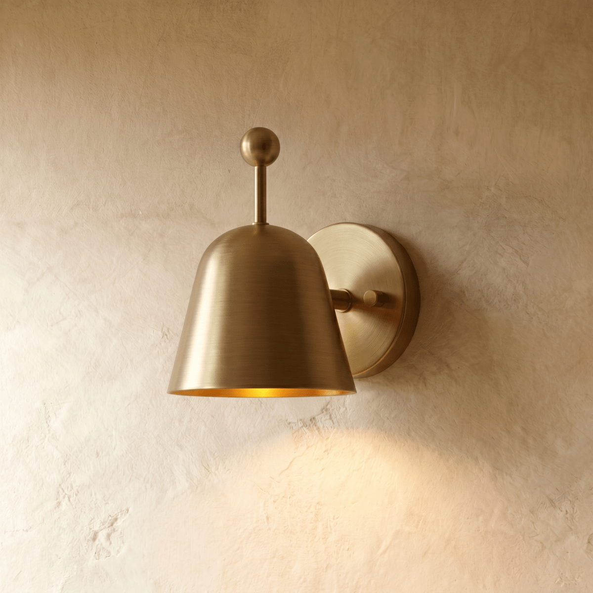 Clérachic wall lamp in polished brass, its bell shade angled down from a slim ball-topped arm.