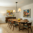 Clérachic chandelier in matte black above a walnut dining table, flanked by bold abstract paintings.