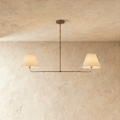 Clérachic chandelier in vintage brass, twin linen drum shades on a horizontal bar overhead.