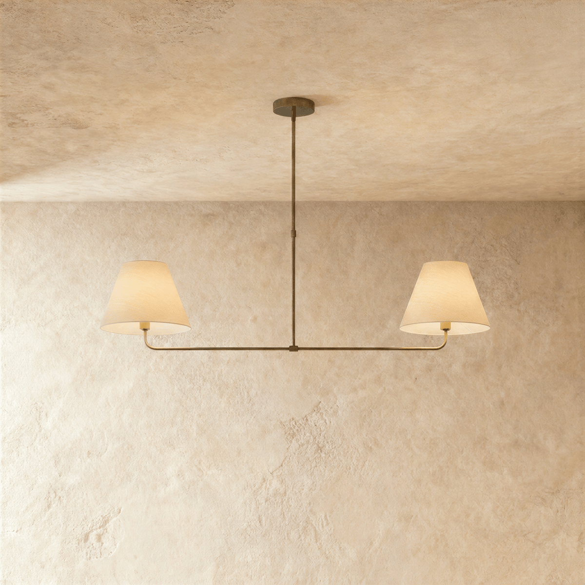 Clérachic chandelier in vintage brass, twin linen drum shades on a horizontal bar overhead.