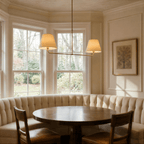 Clérachic chandelier in brushed brass above a round table in a curved bay-window breakfast nook.