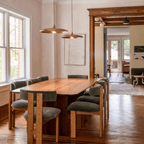 Clérachic vintage brass saucer pendant lights paired above a dining table in a room with dark timber door trim.