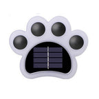 The unlit light on white, its white paw body holding four black toe lenses around a solar panel.