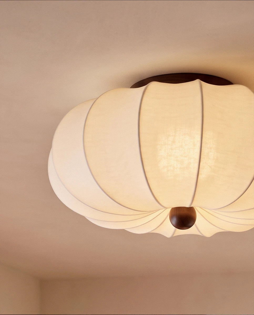 Clérachic ceiling light detail, a closer view of the scalloped fabric shade and dark wood finial glowing warm.