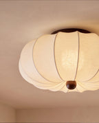 Clérachic ceiling light detail, a closer view of the scalloped fabric shade and dark wood finial glowing warm.