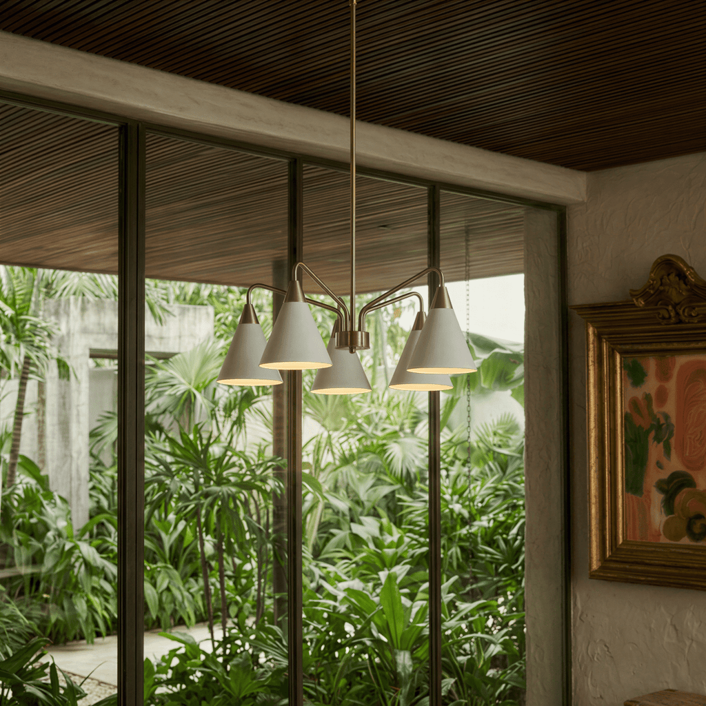 A Clérachic five-arm chandelier hangs before glass doors opening onto a lush tropical garden.