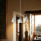 This Clérachic three-arm chandelier glows warmly beneath a wood-slat ceiling in a sunlit Mediterranean room.