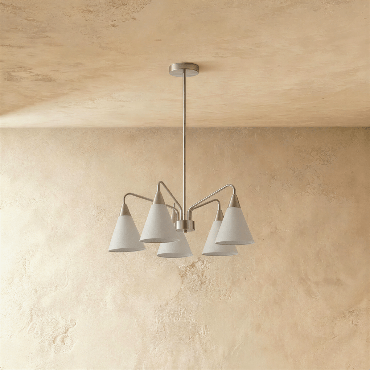 A Clérachic chandelier drops from the ceiling on a slim rod, its five white cone shades angled outward.