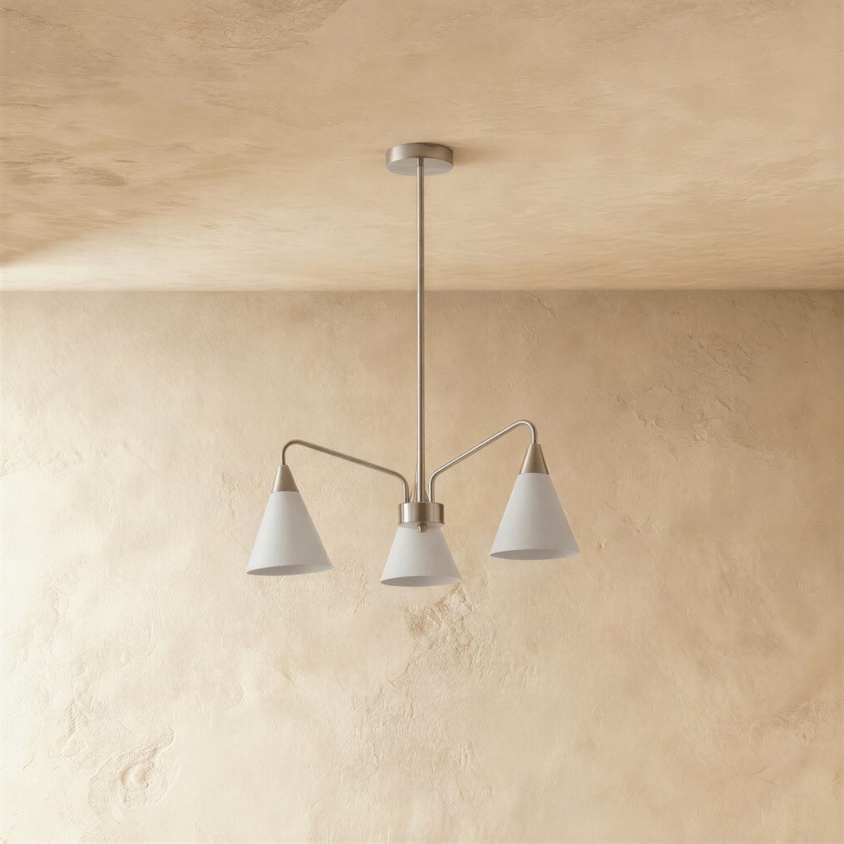 A Clérachic chandelier with three white cone shades hangs from a slim rod against a textured plaster wall.