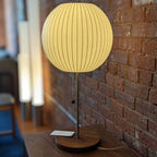 Faux silk bubble table lamp with chrome stem lit warmly on a side table