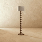 Clérachic stacked-sphere wood floor lamp in walnut, unlit so the rounded spheres and the narrower necks between them read clearly above the flat round base.