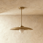 Clérachic dish-shaped pendant light in the Brass finish, shown unlit so the globe reads as a plain matte white sphere hanging below the rim.