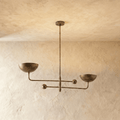 Clérachic chandelier in vintage brass, its two balanced arms and bowl shades hung from a plaster ceiling.
