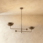 Clérachic chandelier in vintage brass, its two balanced arms and bowl shades hung from a plaster ceiling.