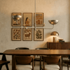 Clérachic chrome chandelier hanging above a dining table beside a gallery wall of framed folk-art prints.