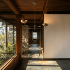 Clérachic vintage brass chandelier hanging in a stone-and-timber hallway overlooking hills through a window.