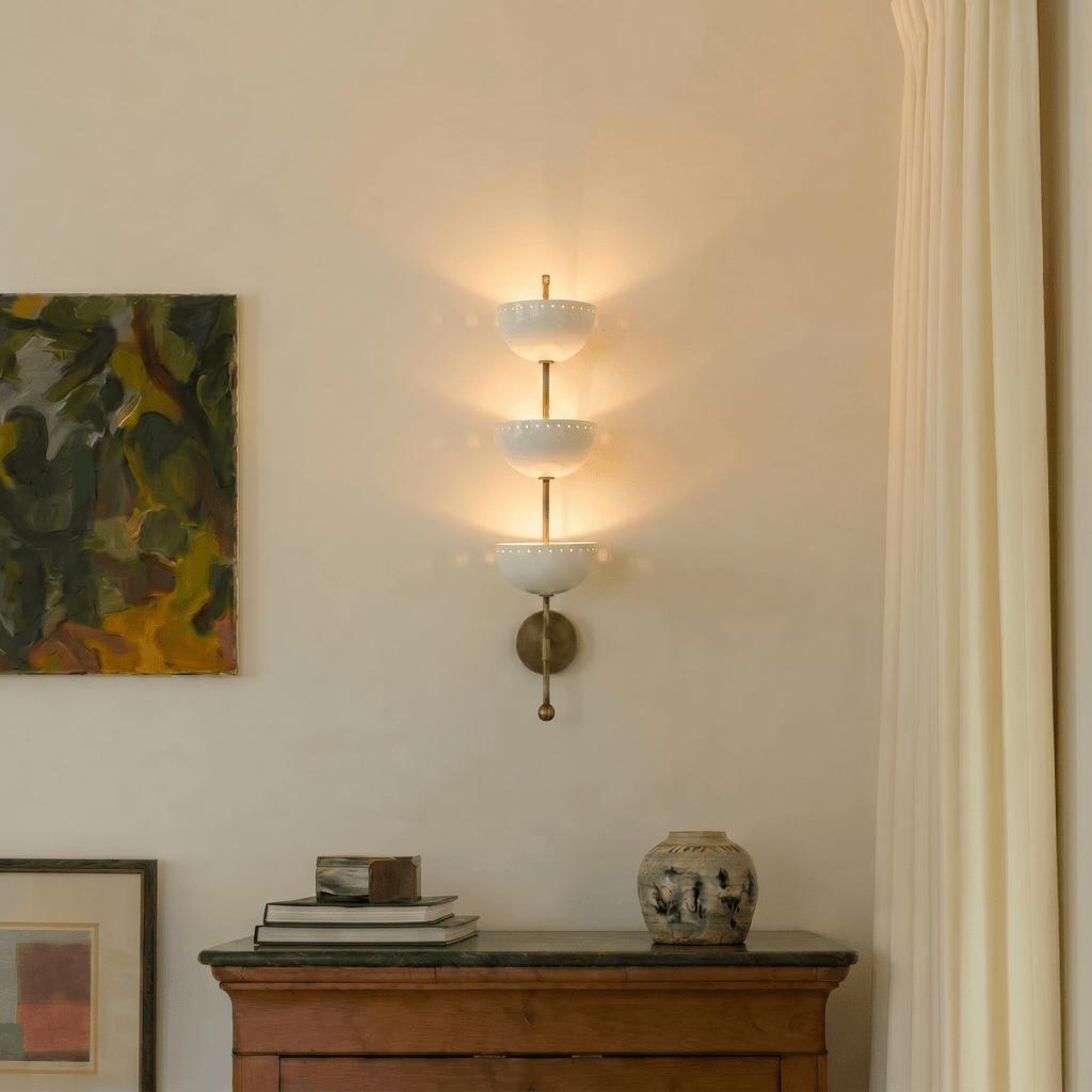 Clérachic brass three-tier bowl sconce lit beside a framed abstract painting above a wooden sideboard.