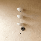 Clérachic three-tier bowl sconce in matte black, shown from a slightly closer studio angle on a plaster wall.