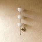 Clérachic three-tier bowl sconce in vintage brass, shown from a slightly closer studio angle on a plaster wall.