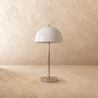 A chrome Clérachic table lamp viewed from a different angle, the white dome shade lit warmly.