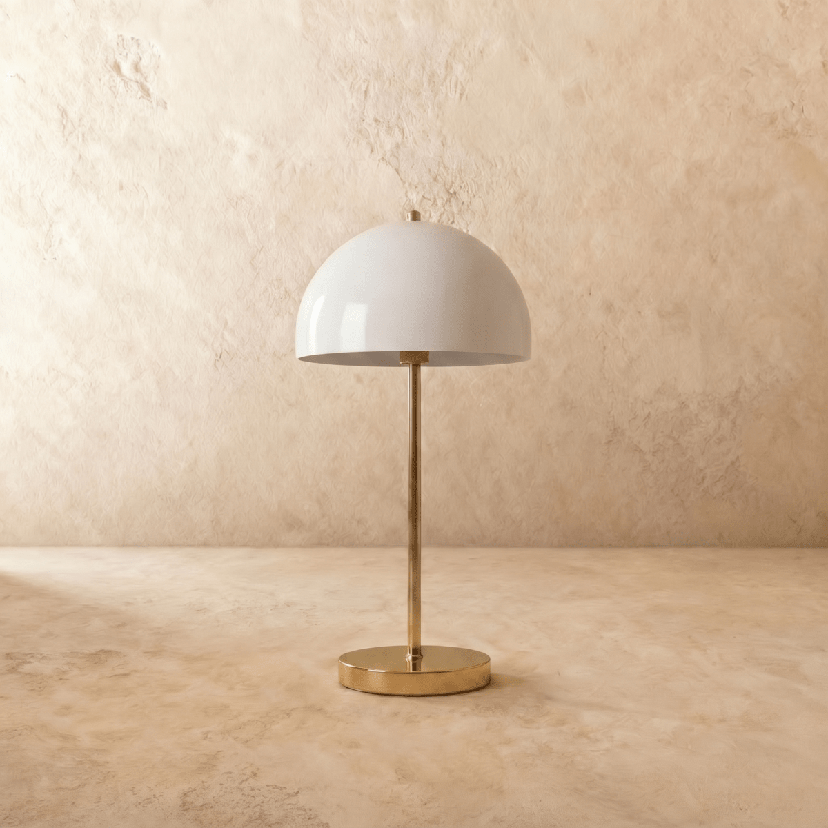 A polished brass Clérachic table lamp viewed from a different angle, the white dome shade lit warmly.