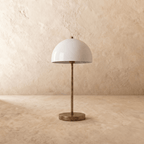 This vintage brass Clérachic table lamp is shown from another angle, its white dome shade glowing softly.