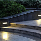 The lights fitted into the side walls of curved stone garden steps, lighting each tread at dusk.