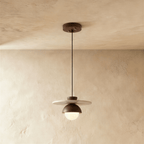 Clérachic pendant light in walnut, a round opal glass globe glowing beneath a wide flat wooden disc.