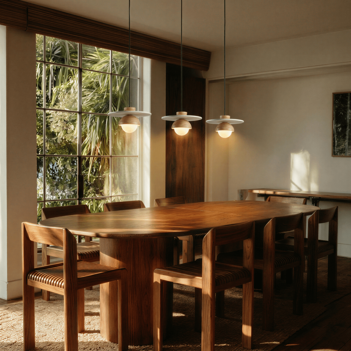 Clérachic pendant lights in light wood hanging above a sunlit dining table with woven wood chairs.