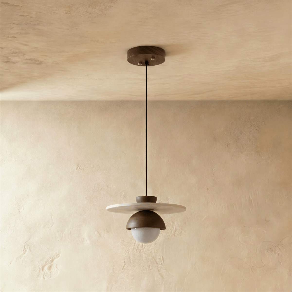 Clérachic pendant light in walnut, the flat disc and glass globe viewed from another angle overhead.
