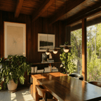 Clérachic pendant lights in walnut glowing above a wood-paneled dining nook with three fixtures in a row.
