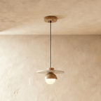 Clérachic pendant light in a light wood finish, a round opal glass globe glowing beneath a wide flat disc.