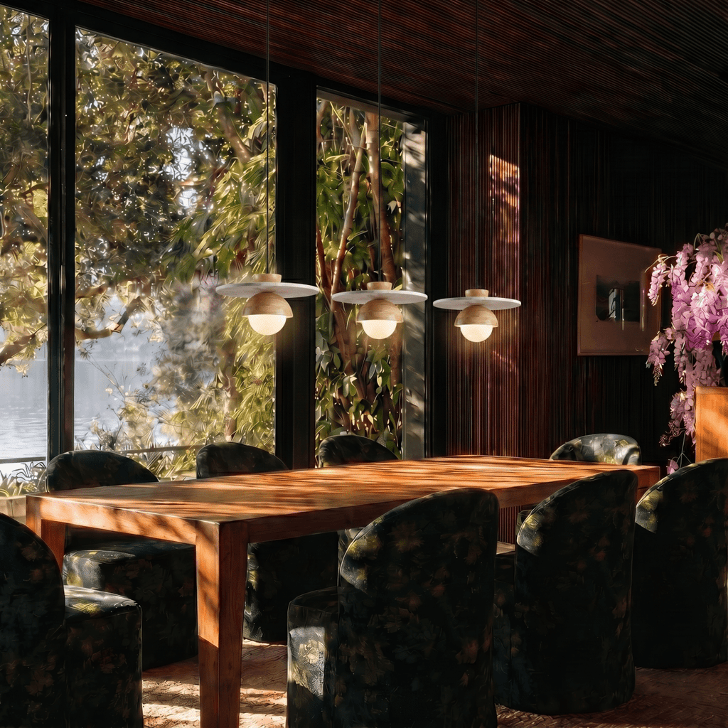 Clérachic pendant lights in light wood, three fixtures glowing above a dining table with a lake view beyond.