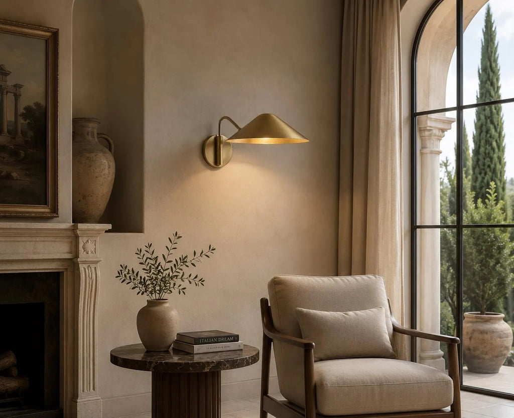 Video: a Clérachic brass cone-shade wall light glowing beside a fireplace and an arched window