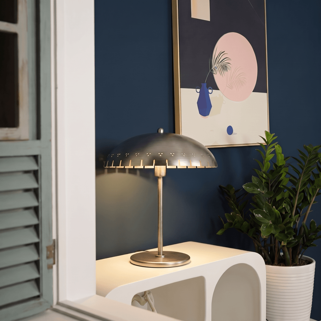 Clérachic table lamp in chrome glowing on a console beside shuttered doors and framed still-life art.