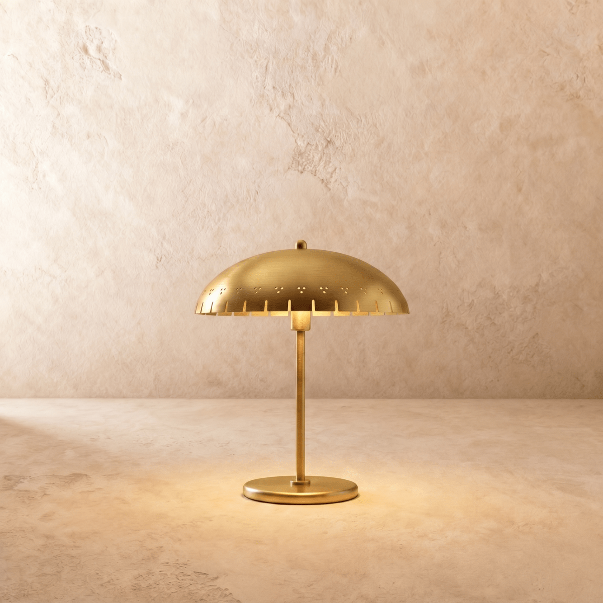 Clérachic table lamp in a warm satin brass finish, a perforated dome shade glowing on a slender stem.