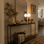 Clérachic table lamps in matte black, two fixtures glowing on a console table beside a stack of books.