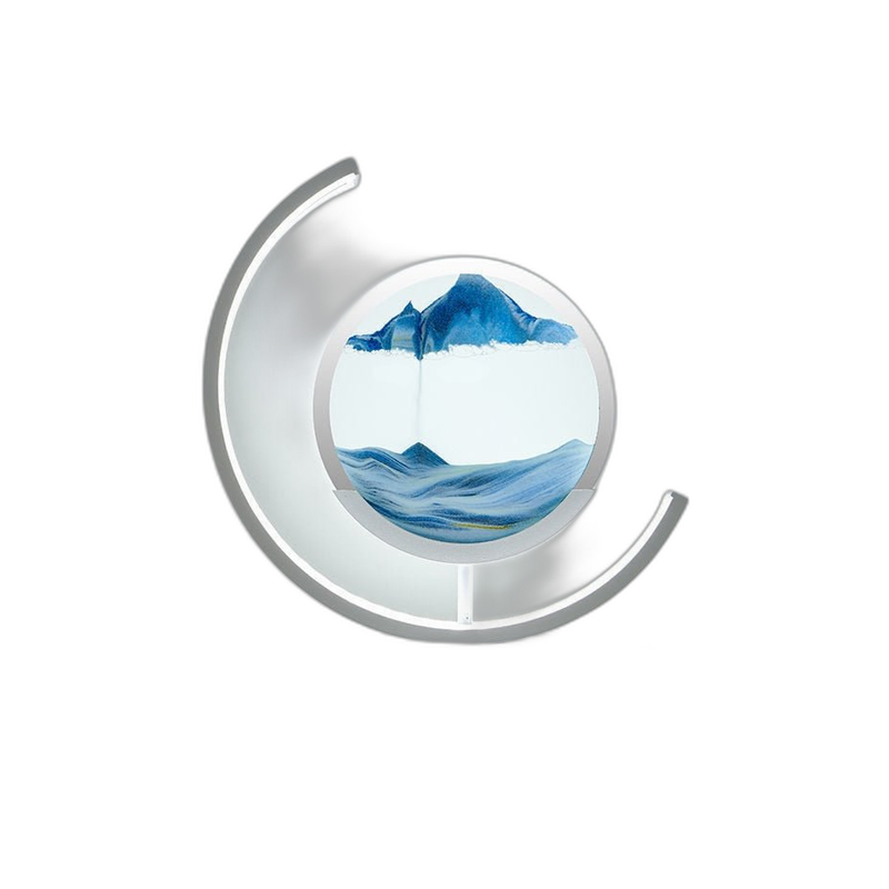 Moving sand art lamp with blue sand forming a peaked mountain landscape in the glass disc