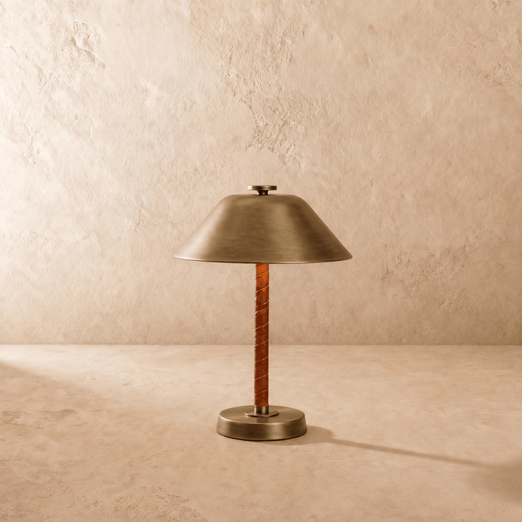 Clérachic table lamp in vintage brass shown from another angle, light spilling beneath the cone shade.