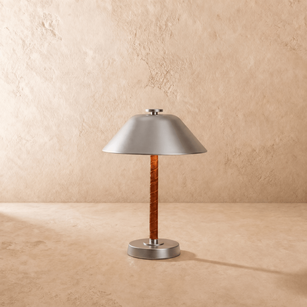Clérachic table lamp in chrome shown from another angle, light spilling beneath the cone shade.