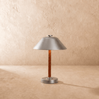 Clérachic table lamp in chrome shown from another angle, light spilling beneath the cone shade.