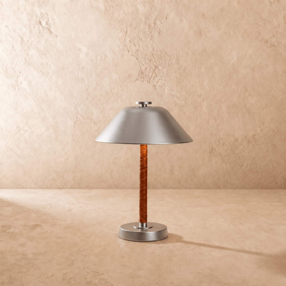 Clérachic table lamp in chrome shown from another angle, light spilling beneath the cone shade.