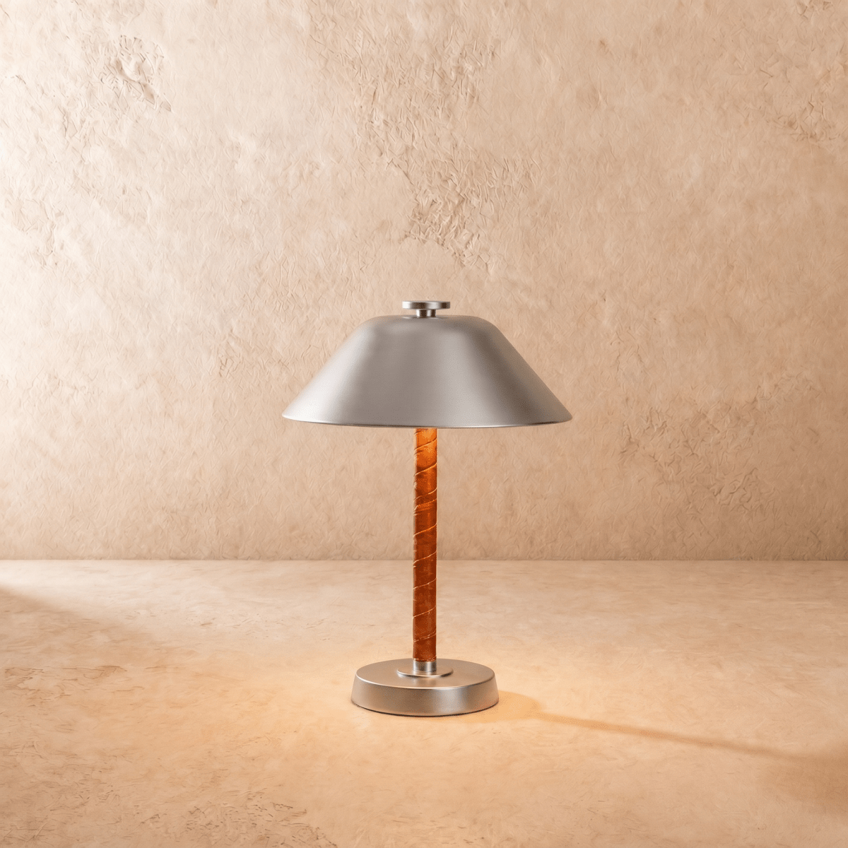 This Clérachic table lamp in chrome, a cone metal shade over a cognac leather-wrapped stem.