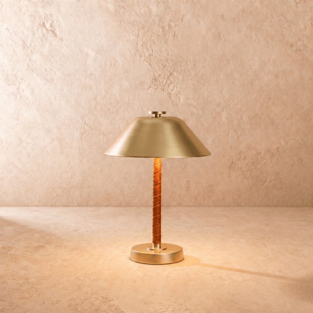 Clérachic table lamp in brushed brass, the cone metal shade set above a leather-wrapped stem.