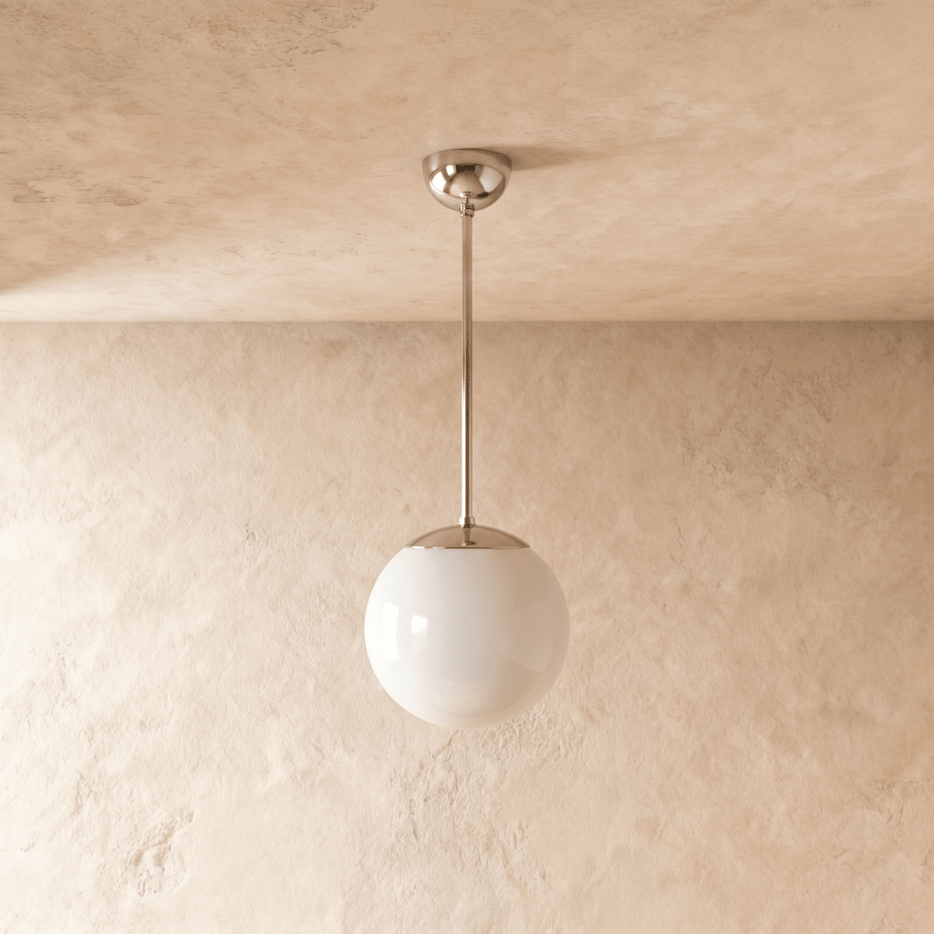 Clérachic globe pendant light in chrome, shown from a slightly closer studio angle against a plaster wall.
