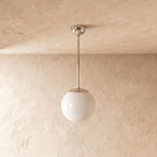 Clérachic globe pendant light in chrome, shown from a slightly closer studio angle against a plaster wall.